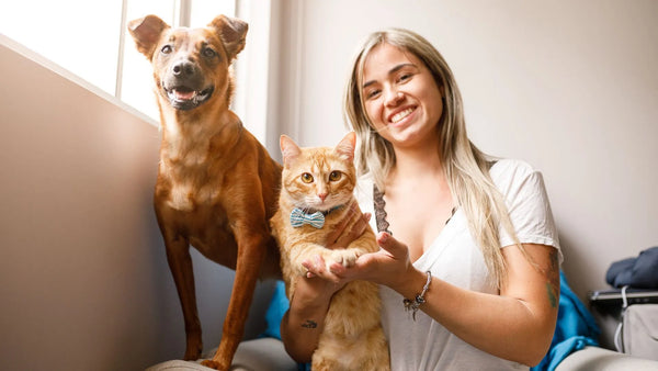 A blonde-haired woman is posing for the camera with her cat and dog.